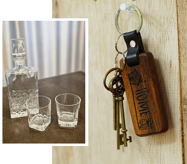 Two vintage keys with a wooden keychain and a glass decanter with two glasses.